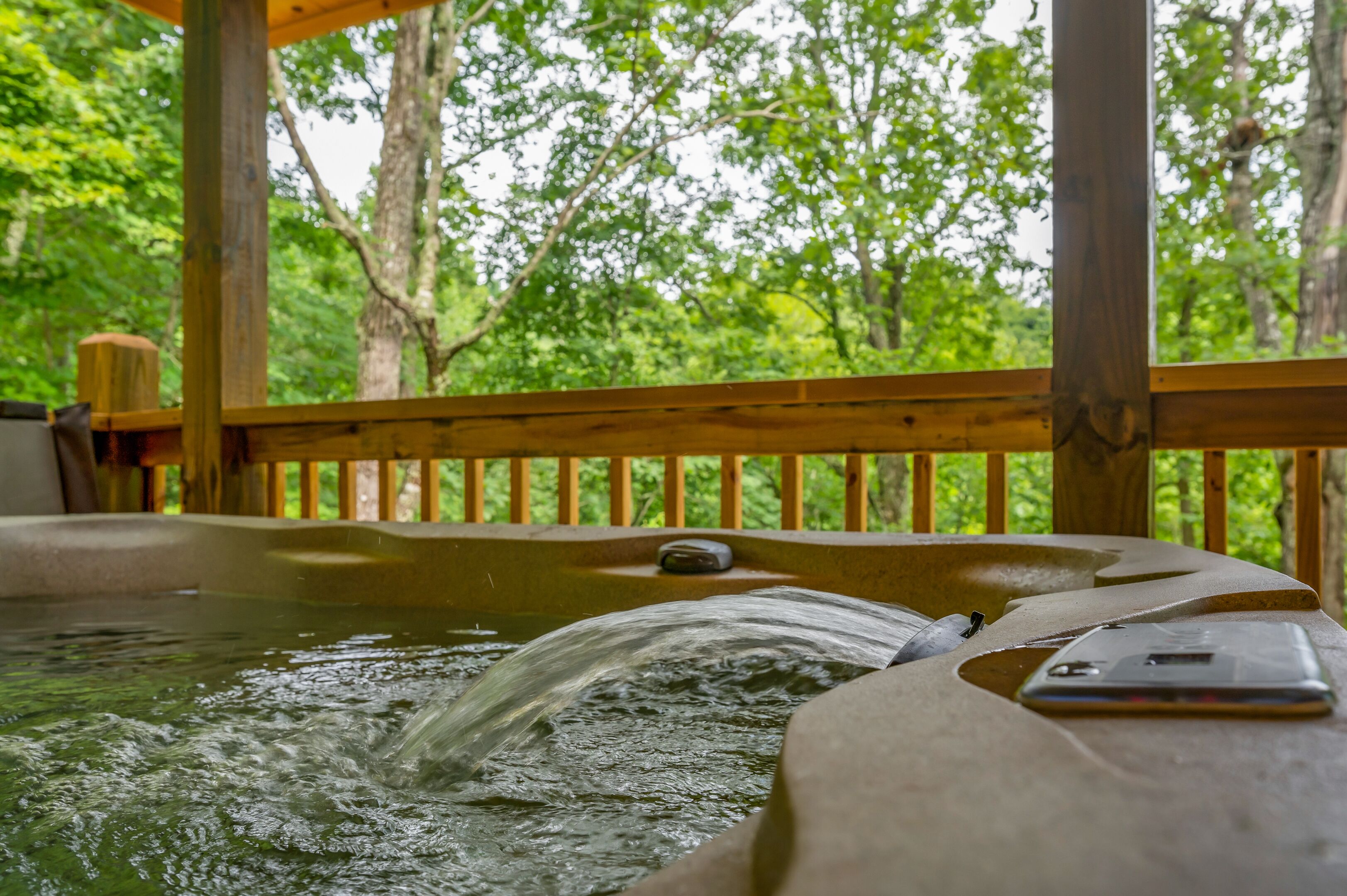A hot tub with a wooden deck and a smartphone on it.