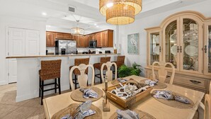 A modern kitchen with a central island, wooden cabinets, and a dining area with a large wooden cabinet and chairs.