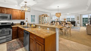 A spacious kitchen with granite countertops, wooden cabinets, and stainless steel appliances.