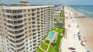 A high-rise hotel with multiple balconies, a pool, and a beachside location.