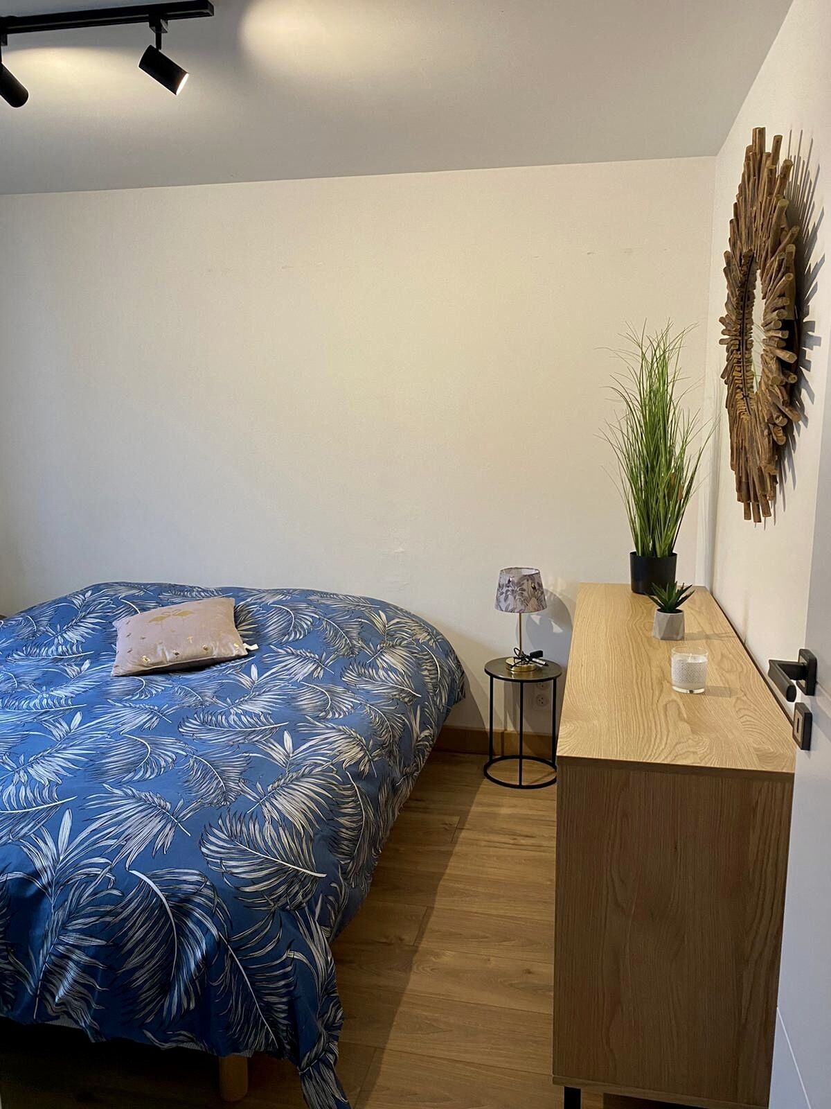 Ein Schlafzimmer mit Bett, Nachttisch, Lampe und Wanddekoration.