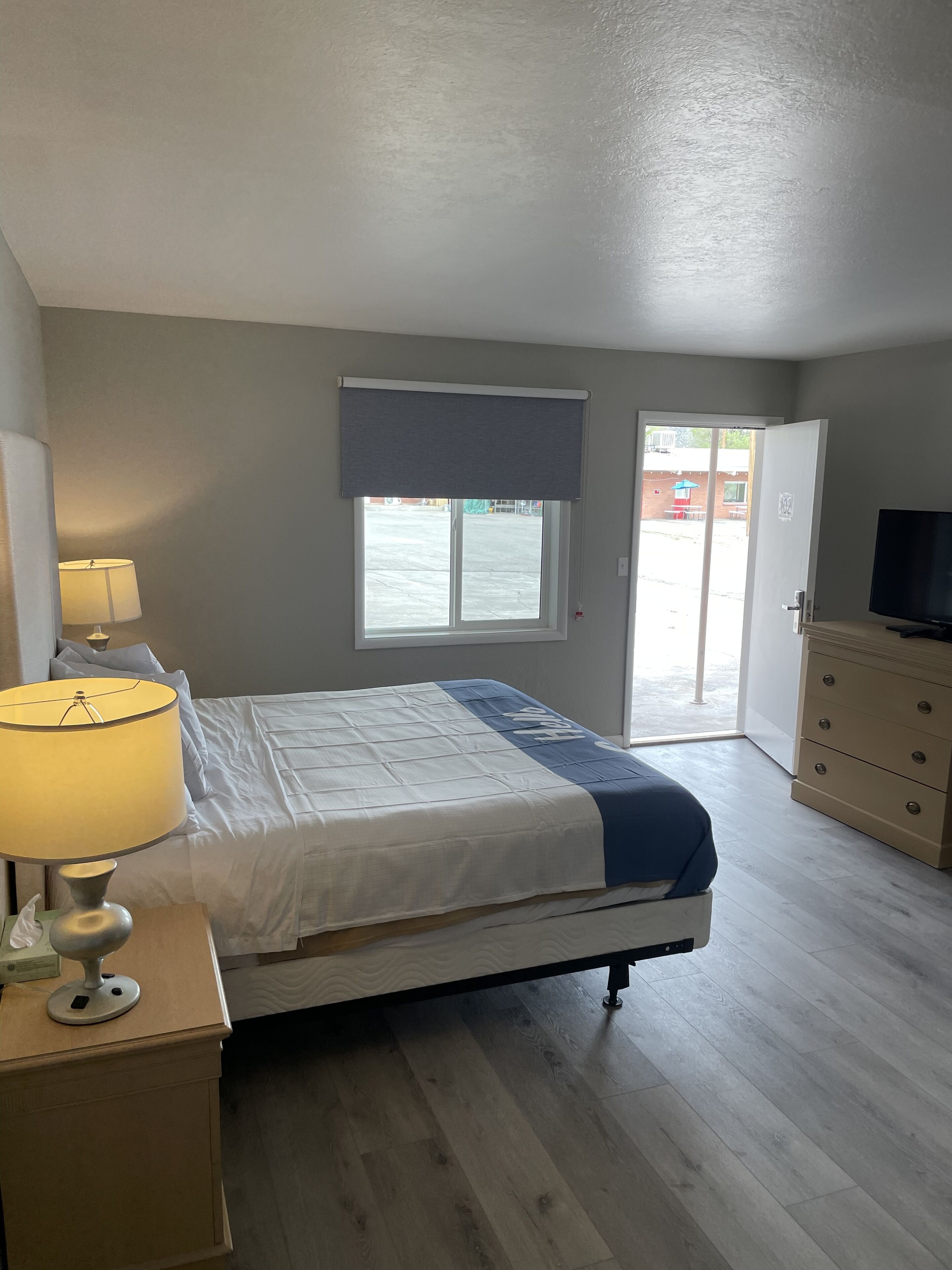 Ein Schlafzimmer mit Bett, Nachttischlampe, Kommode und Fernseher.