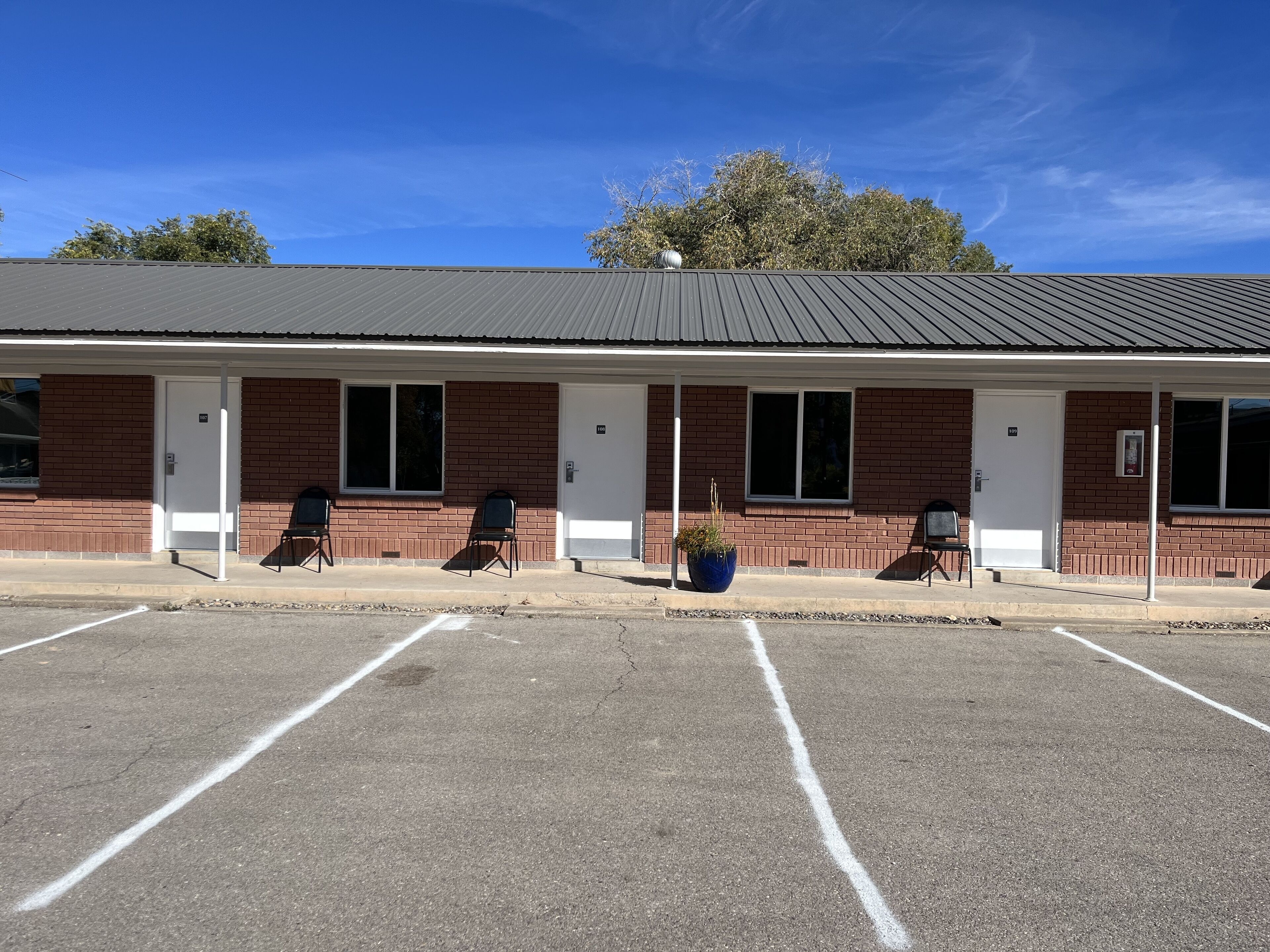 A motel with a brick facade, multiple windows, and a parking lot.