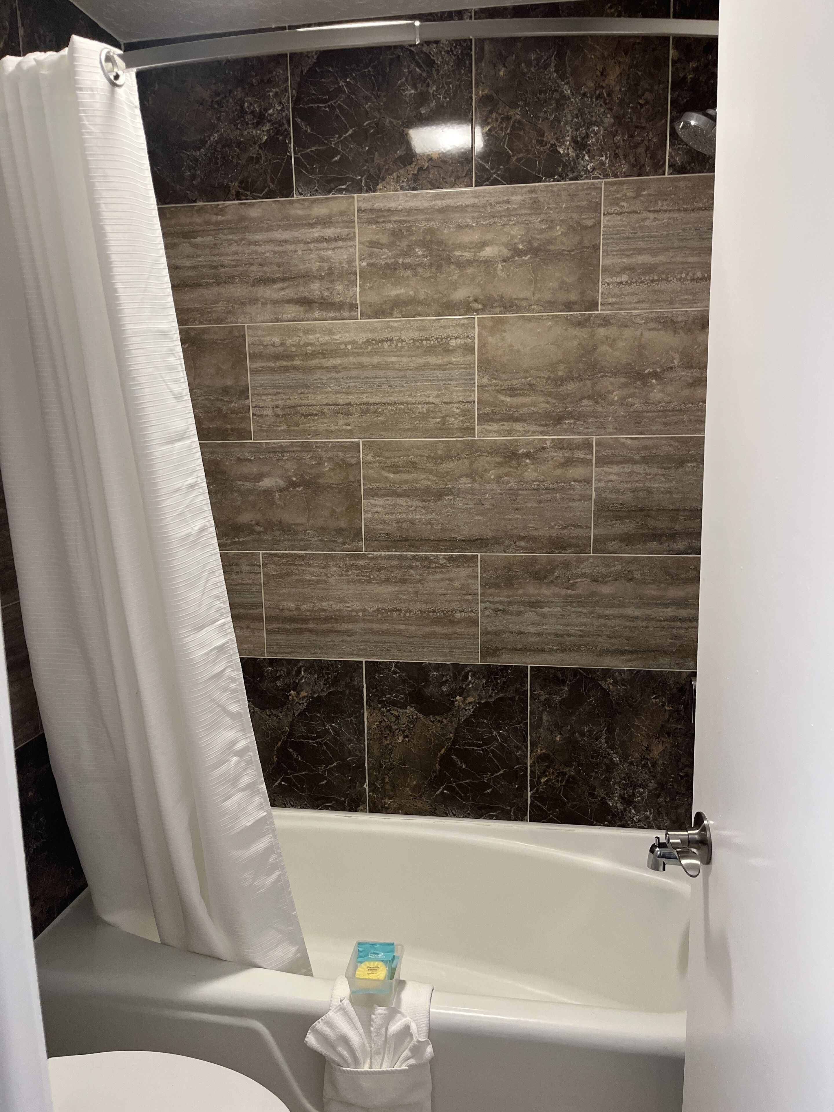 Ein Badezimmer mit Badewanne, Duschvorhang und Fliesen.