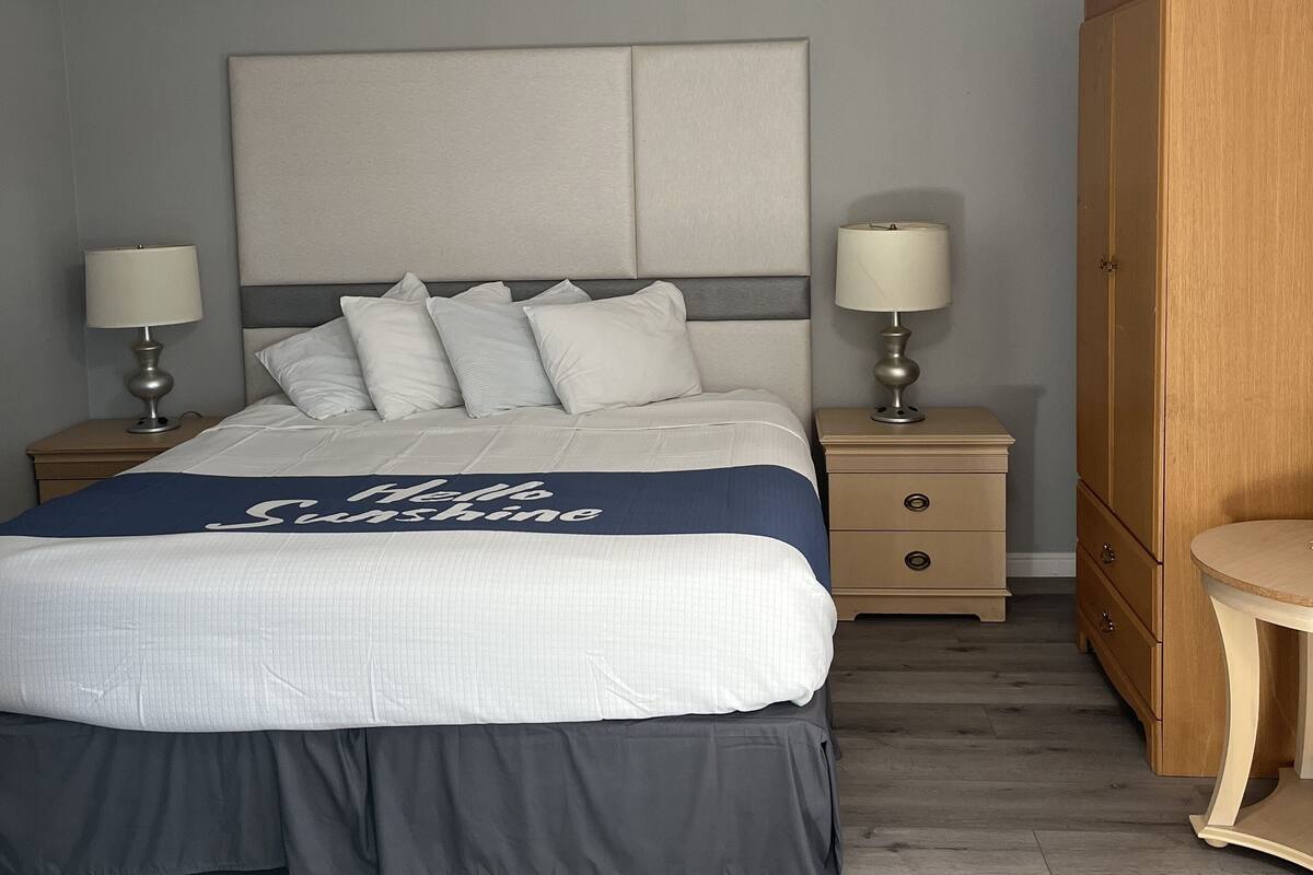 A neatly arranged bedroom with a bed, bedside tables, a wardrobe, and a nightstand.