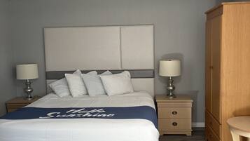 A neatly arranged bedroom with a bed, bedside tables, a wardrobe, and a nightstand.