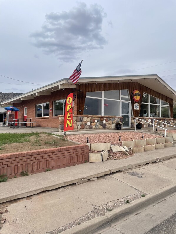 A restaurant with an American flag, a 'OPEN' sign, and a stone facade. - Sunglow Hotel (Bicknell)