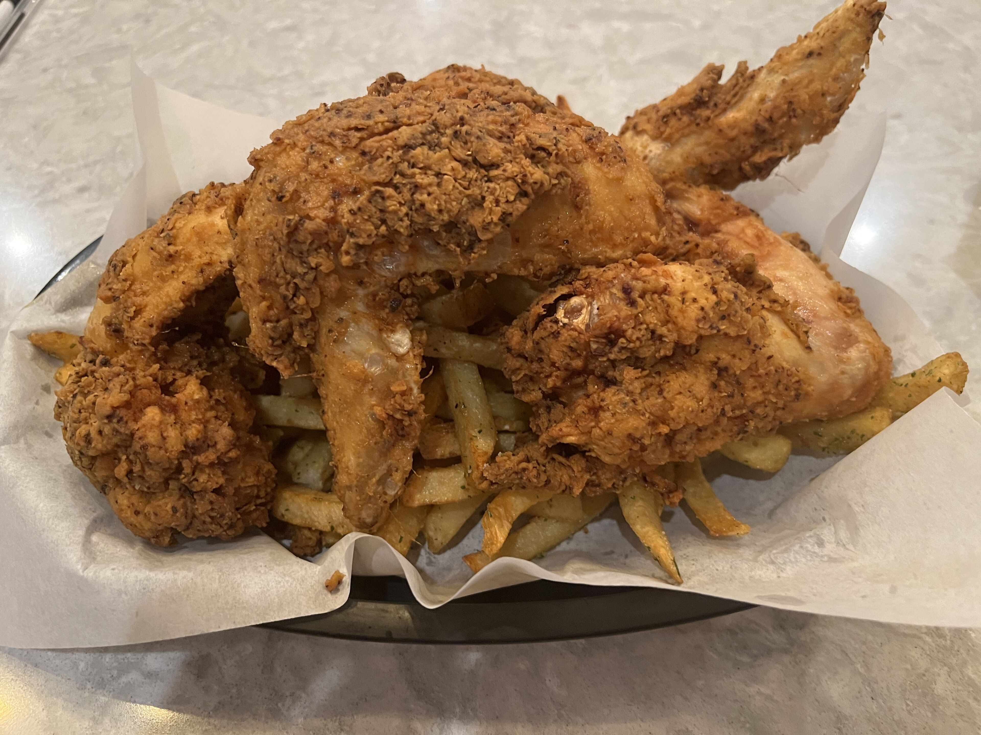 Un cesto con pollo frito y papas fritas.