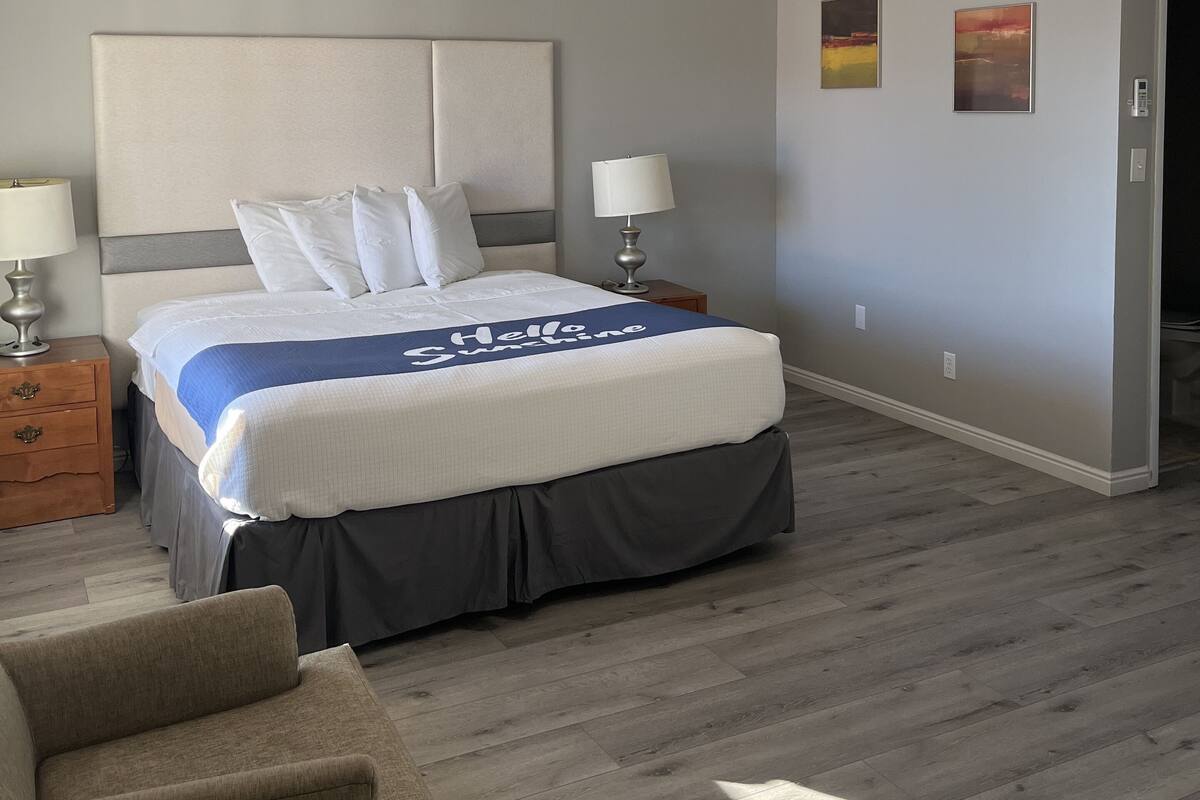 A hotel room with a bed, bedside tables, a chair, and a ceiling light.
