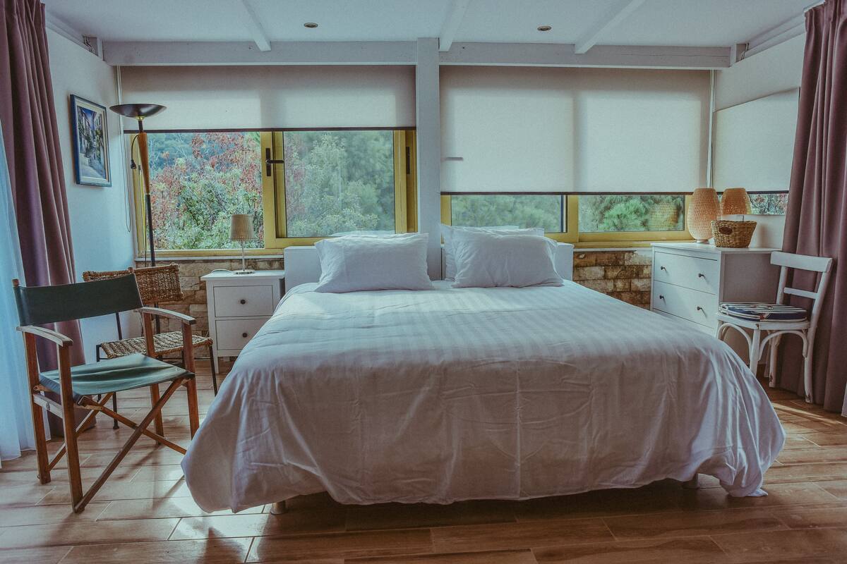 A bedroom with a large bed, two nightstands, a dresser, and a chair.