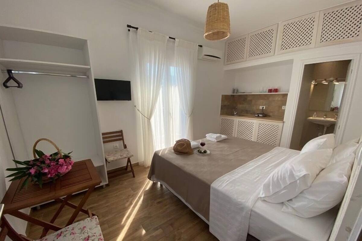 A hotel room with a bed, a desk with a chair, a wardrobe, and a bathroom.