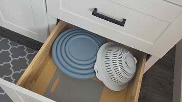 Un cajón de cocina con un colador azul y un escurridor blanco.