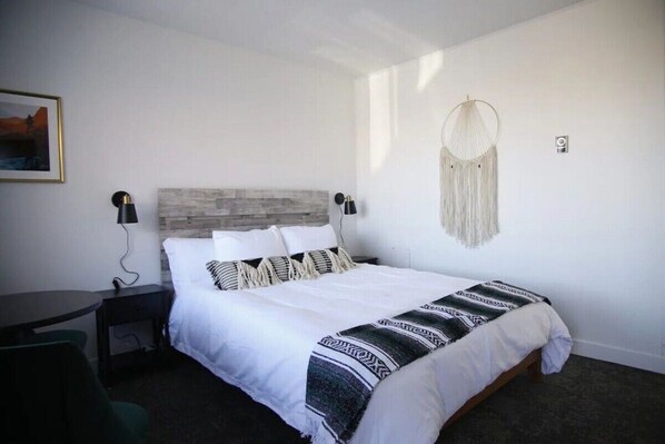 A bedroom with a bed, bedside tables, a desk, and a chair. - Fillmore Lodge: Bright Queen Room, Lowest Price! (Fillmore)