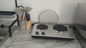 A kitchen with a stove, sink, and utensil holder.
