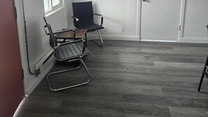 A room with a dark wood floor, a white door, and two black chairs. - Fillmore Lodge: One King Room with Lowest Rates! (Fillmore)