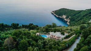 Une propriété située sur la côte, dotée d’une piscine, entourée d’une végétation luxuriante et offrant une vue sur la mer.