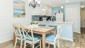 Una cocina moderna con una isla central, armarios blancos y una pared de acento azul.