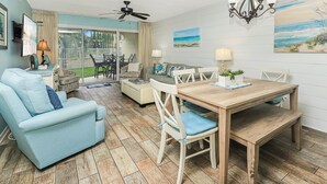 Una sala de estar amplia con una mesa de comedor de madera, sillones azul claro y un sofá.