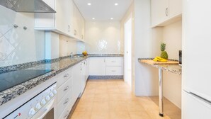 A modern kitchen with white cabinets, a granite countertop, and a stainless steel range hood.