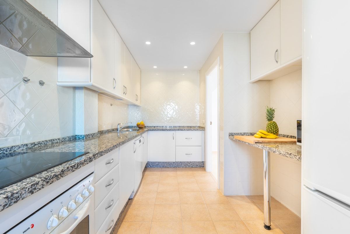 A kitchen with white cabinets, a granite countertop, and a stainless steel range hood.