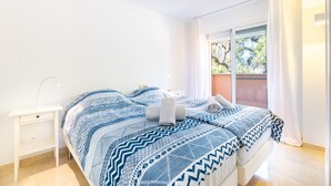 A bedroom with a bed, a nightstand, and a window with curtains.
