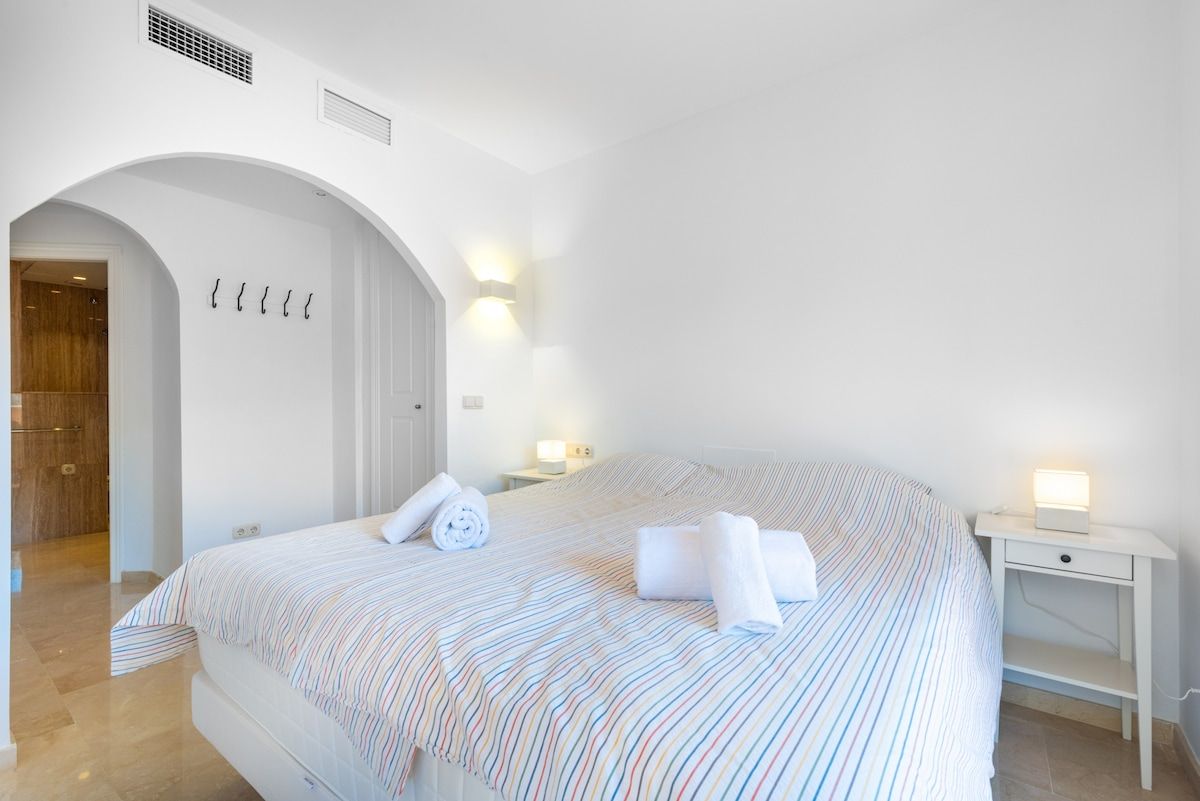 Ein Hotelzimmer mit einem großen Bett, einem weißen Bogenportal und einer Wandleuchte.