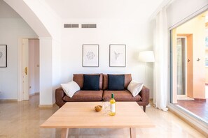 Ein modernes Wohnzimmer mit einem braunen Ledersofa, einem Holztisch und zwei gerahmten Kunstwerken an der Wand.