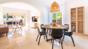 A spacious dining area with a round table, black chairs, and a woven pendant light.