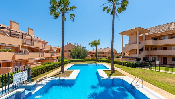 A swimming pool surrounded by palm trees and apartment buildings.