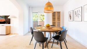 A modern dining area with a round table, black chairs, and a hanging pendant light.