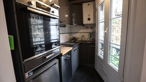 A compact kitchen with a built-in oven, a sink, and a window providing natural light.