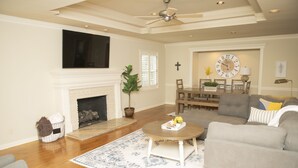 A living room with a fireplace, a dining area, and a ceiling fan.