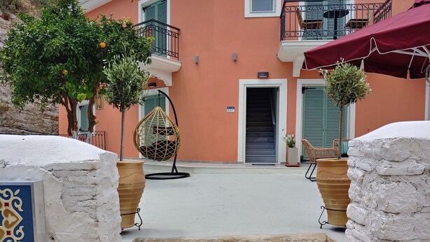 A hotel entrance with a stone staircase, a hanging chair, and potted plants. - Saint George Hotel Parga (Parga)