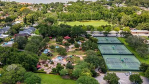 An aerial view of a residential area with houses, a tennis court, and a park with playgrounds.