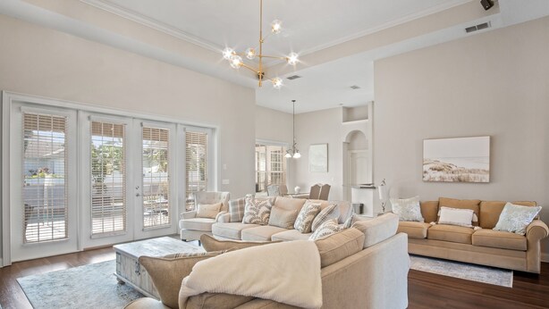 A spacious living room with a beige sofa set, a coffee table, and a chandelier.