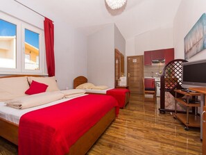 Habitación de hotel con dos camas, televisión, escritorio y vistas al exterior.