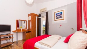 Une chambre d’hôtel équipée d’un lit, d’une télévision, d’une armoire, d’un miroir et d’une fenêtre donnant sur un paysage agréable.