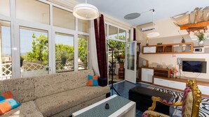 A spacious living area with a sofa, a coffee table, a TV, and a decorative chair.
