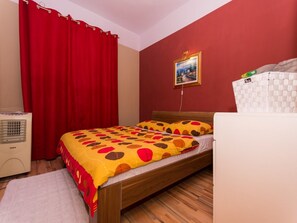 Ein Schlafzimmer mit einem hölzernen Bett, roten Vorhängen, einem weißen Heizkörper und einem Gemälde an der Wand.