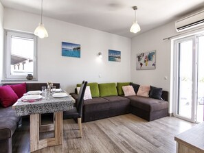 Una sala de estar moderna con una mesa de comedor, un sofá y dos lámparas colgantes.