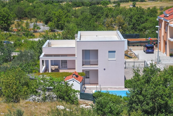 Una casa moderna de dos pisos con techo plano, piscina y jardín.