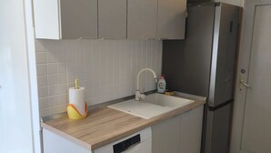 A compact kitchen with a built-in dishwasher, a stainless steel refrigerator, and a white sink with a modern faucet. - Apartment Alba - Three Bedroom Apartment with Loggia (Split)