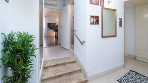 Eine Treppe führt zu einem Wohnbereich mit einem Fernseher, einem Spiegel und gerahmten Fotos an der Wand.