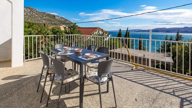 Un balcón con mesa lista para comer, con vistas panorámicas a un lago y montañas.