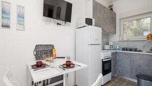 Una cocina compacta con una mesa de comedor, sillas, un refrigerador, un microondas, una estufa y un lavaplatos.