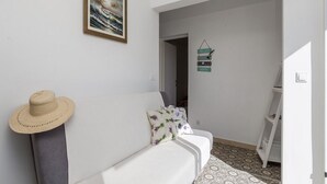 Un sofá blanco con un sombrero de paja, un cuadro enmarcado y un cartel que dice 'BEACH' en la pared.