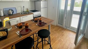 A compact kitchen with white cabinets, a microwave, a stove, and a ceiling fan. - Apartments Sun 4 You - Two Bedroom Apartment with Balcony and Sea View (Karlobag)