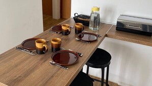 A dining area with a wooden table set for four, including plates, cups, and cutlery. A hanging sign above the table reads "The best wines are the ones we drink with friends." - Apartments Sun 4 You - Two Bedroom Apartment with Balcony and Sea View (Karlobag)