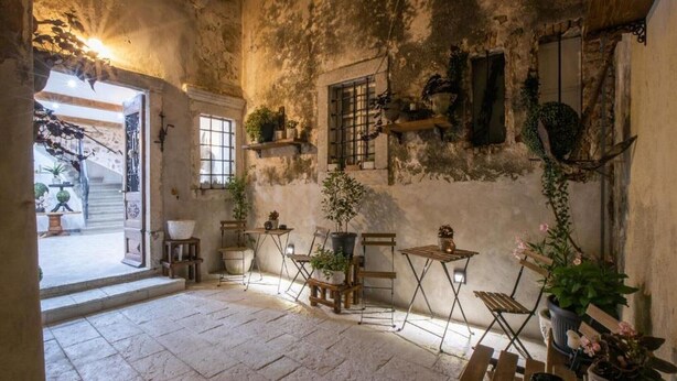 A rustic interior with stone flooring, wooden furniture, and potted plants. - History House Moja Ti 1830 - Superior Apartment with Sauna (Senj)