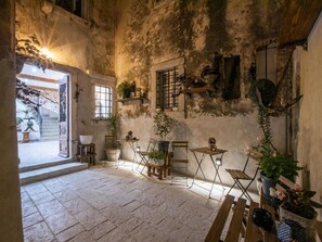 A rustic interior with stone flooring, wooden furniture, and potted plants.
